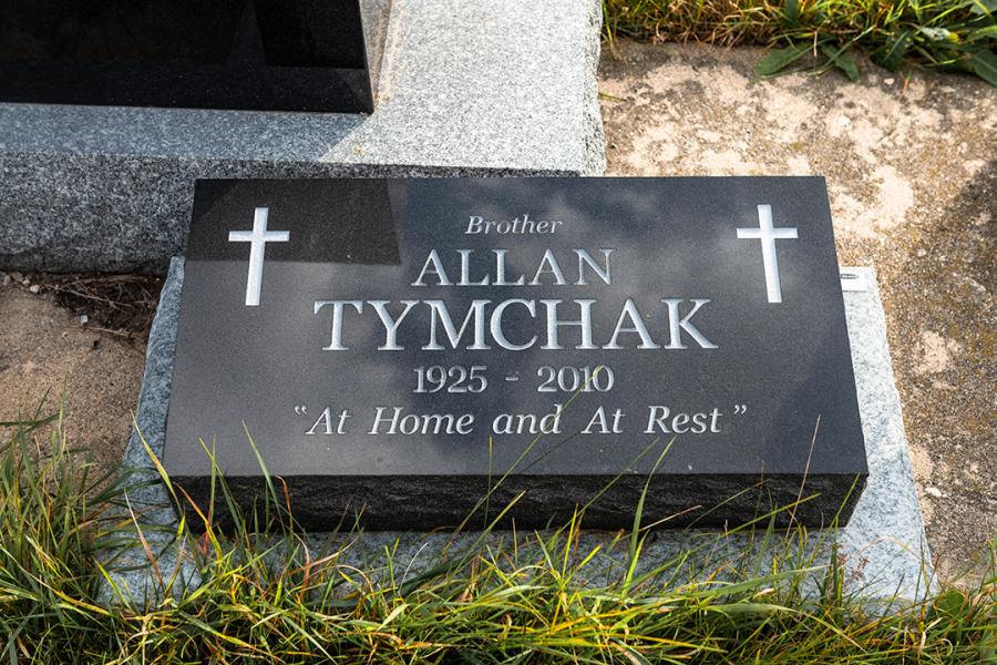Tymchak, a 20 x 10 x 6/4 polished top Midnight Black granite pillow marker installed on a Galaxy Grey granite base installed at the Holy Family Cemetery.