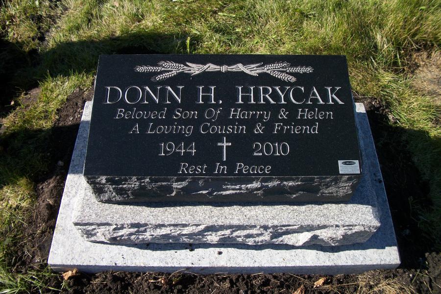Hyrcak, a polished top with all sides rough Midnight Black Pillow marker installed on a Galaxy Grey granite base and a granite foundation.