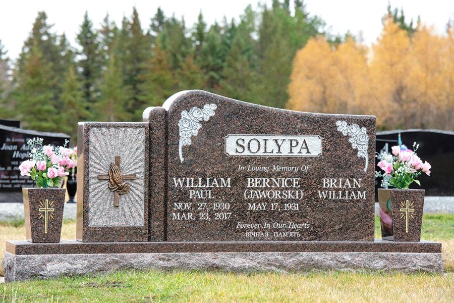 Solypa, Custom Design Memorial with sculptured column. Featured add-ons, Bronze praying hands on cross, matching granite vases, gold paint, on a matching 2" margin polish top base located in Holy Family Cemetery 